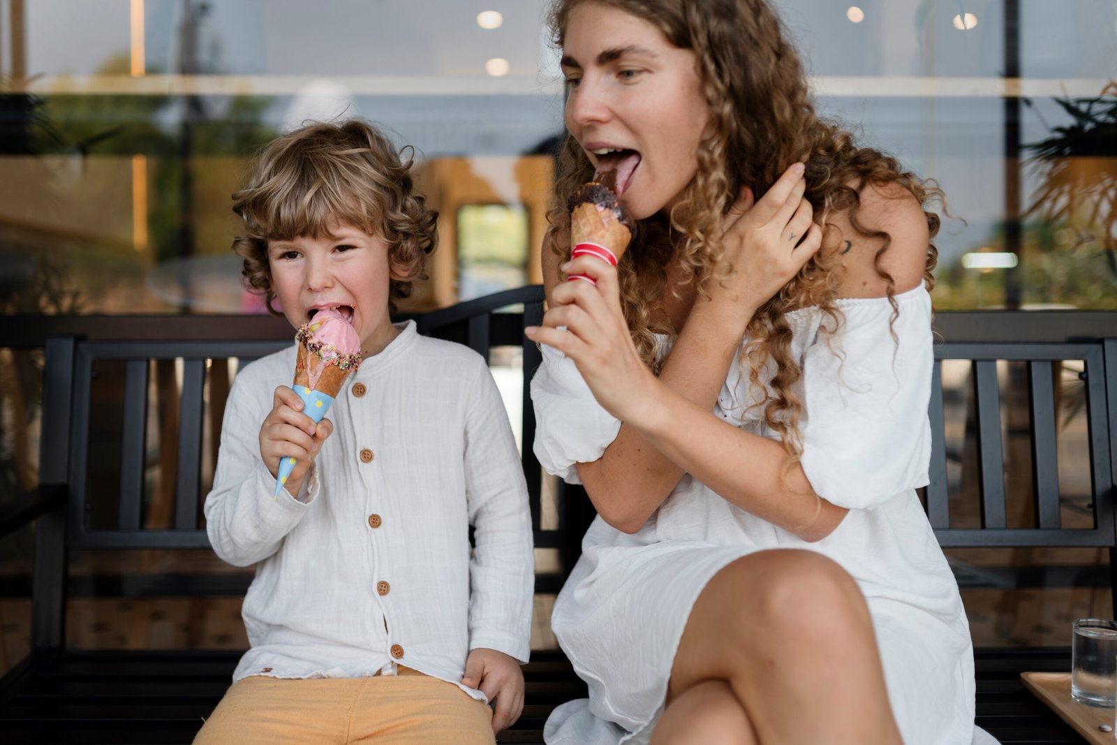 A child sharing ice cream cones with an adult